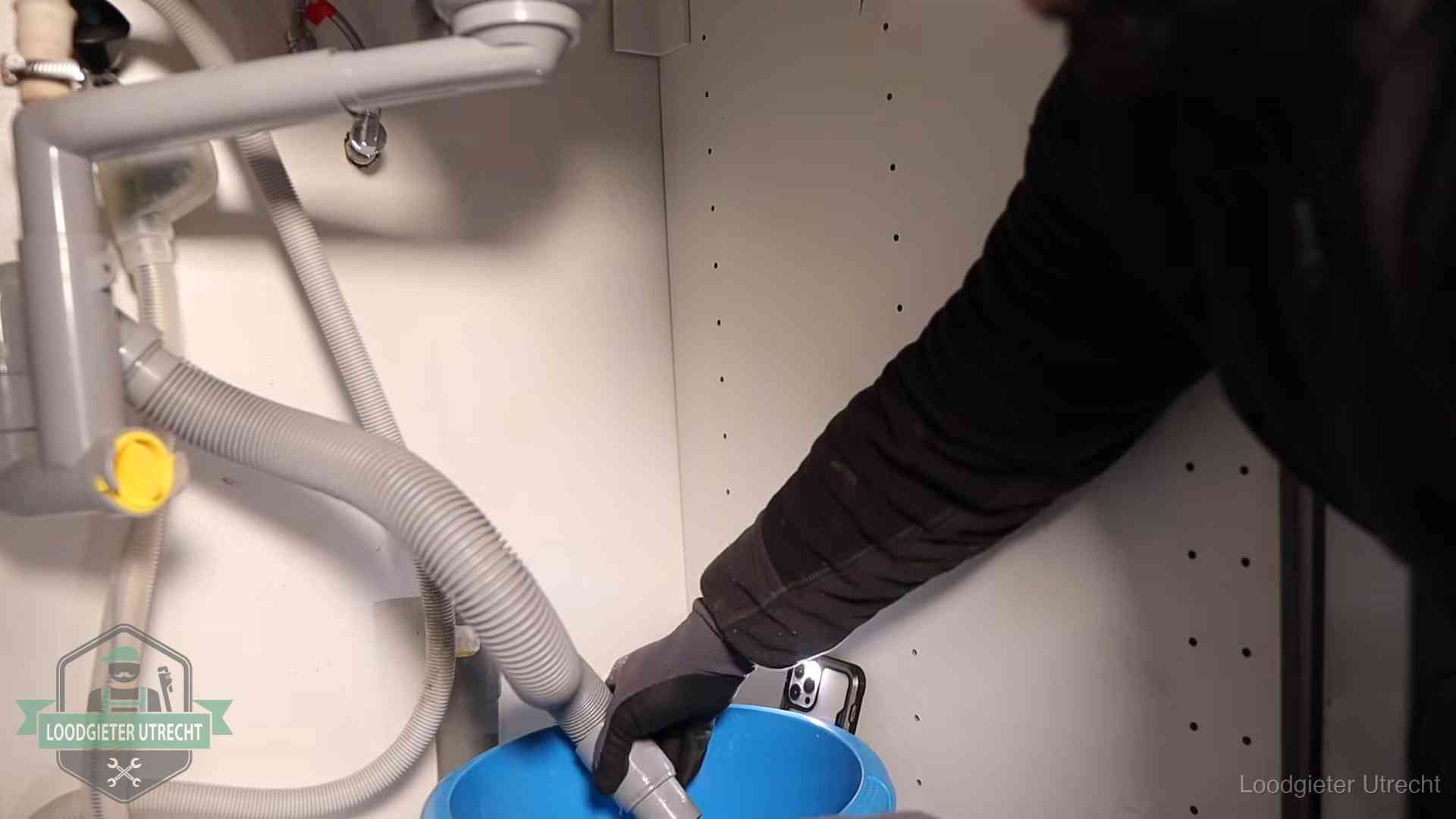 Afvoerslang loopt leeg in een emmer onder de gootsteen in Utrecht, een klus die je zelf kunt doen