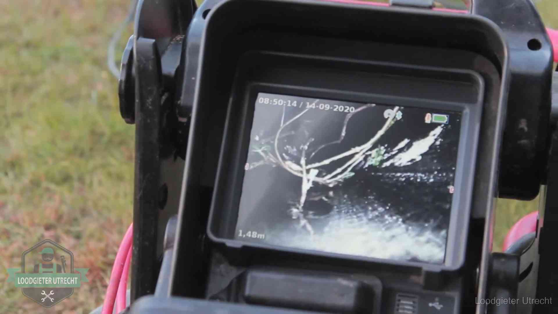 Monitor van een rioolcamera toont wortelingroei in de rioolbuis bij een woning in Utrecht