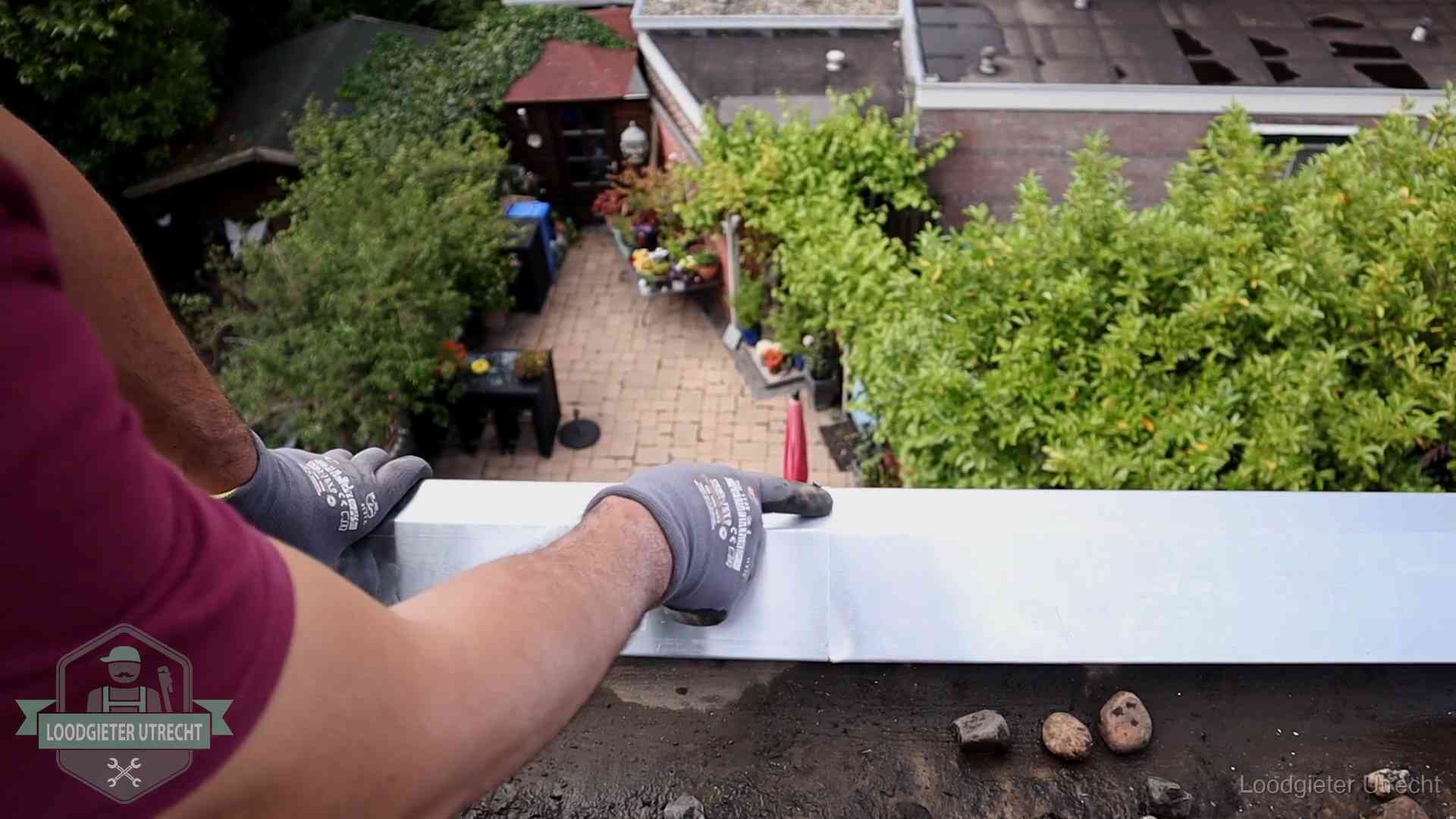 Vakman plaatst een daktrim op de dakrand van een woning in Utrecht