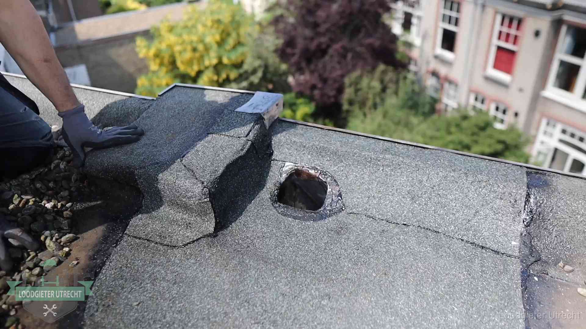 Loodgieter inspecteert een beschadigd bitumen plat dak tijdens een daklekkage-inspectie in Utrecht