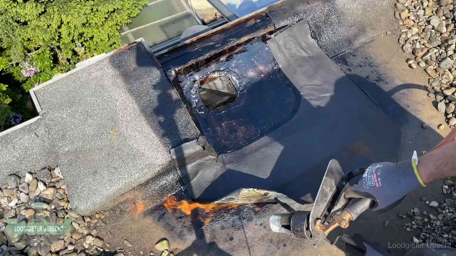 Dakdekker brandt bitumen rond een doorvoer tijdens een daklekkage-reparatie in Utrecht