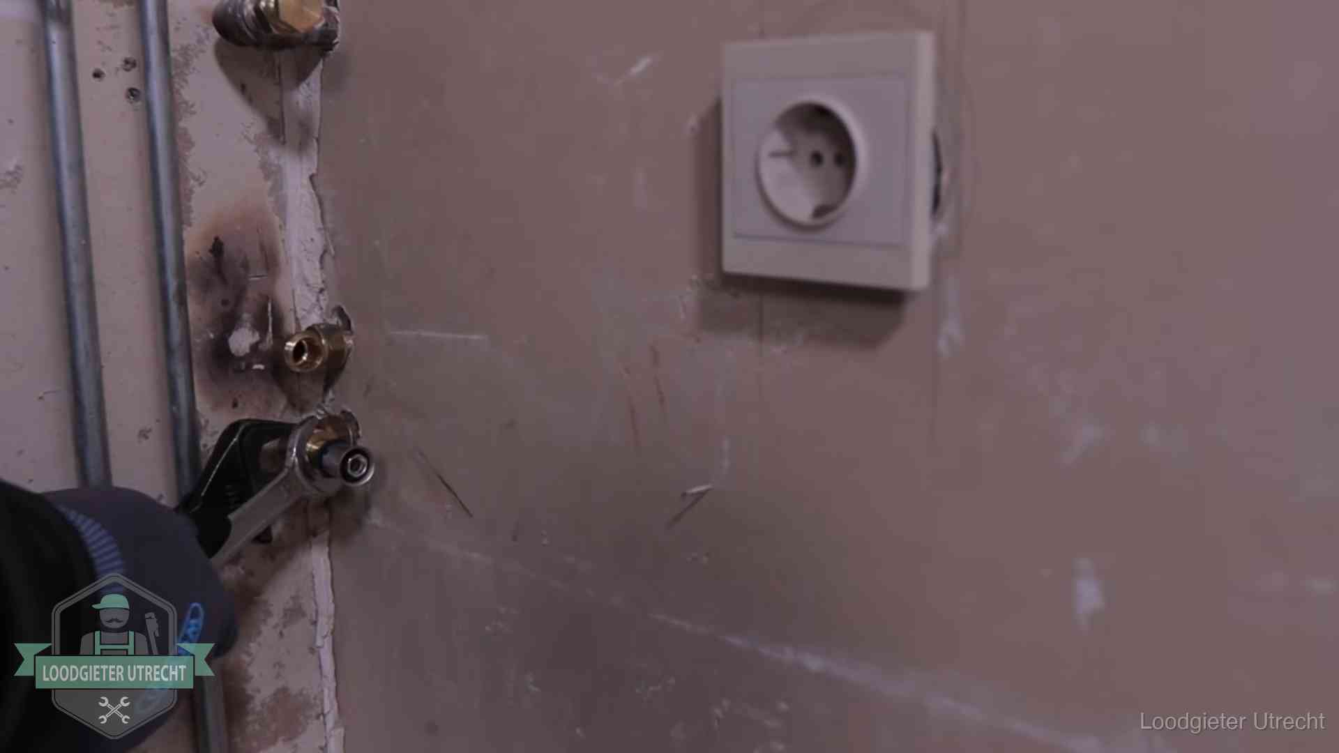 Monteur draait een perskoppeling vast op een leidingaansluiting in Utrecht