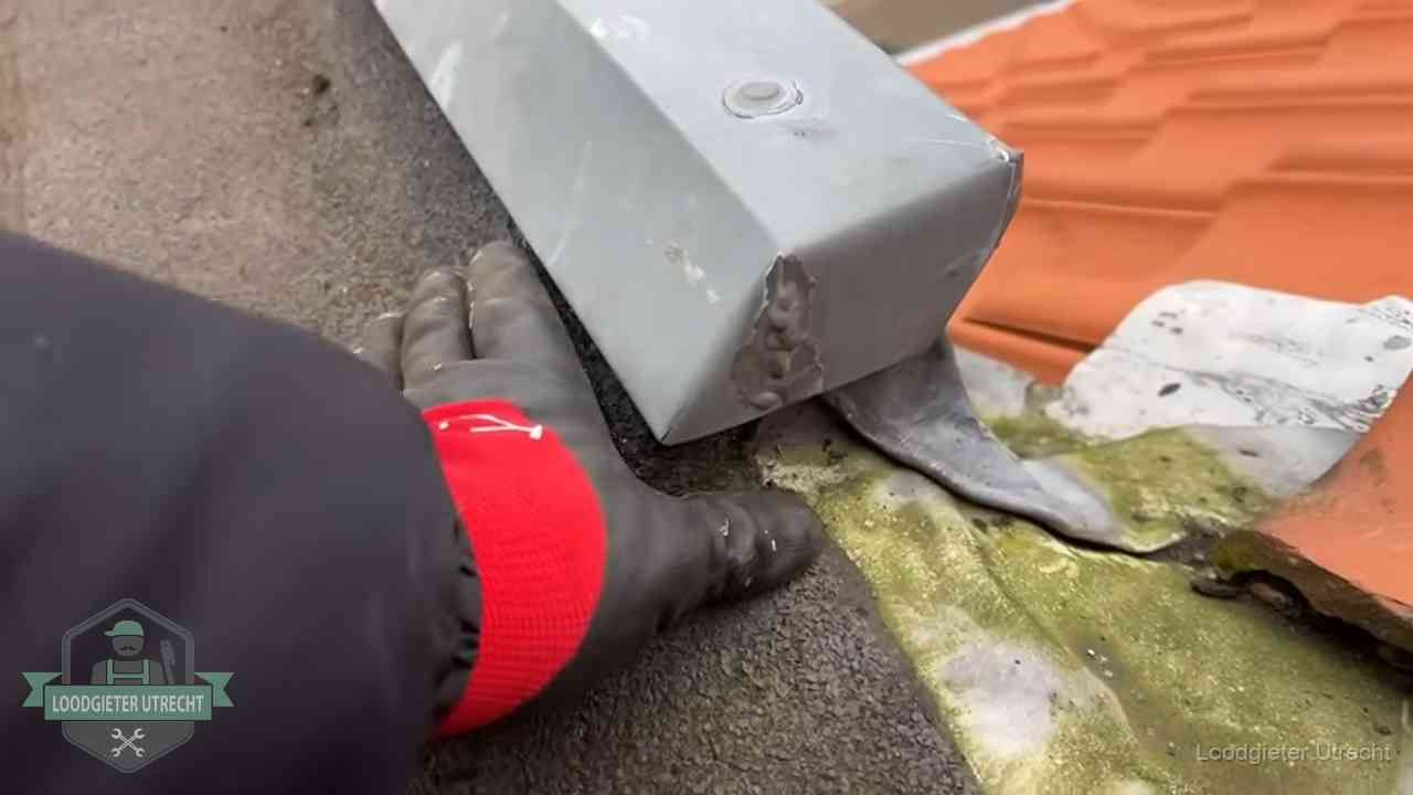 Controle van een zinken hemelwaterafvoer met loodslab bij dakpannen in Utrecht