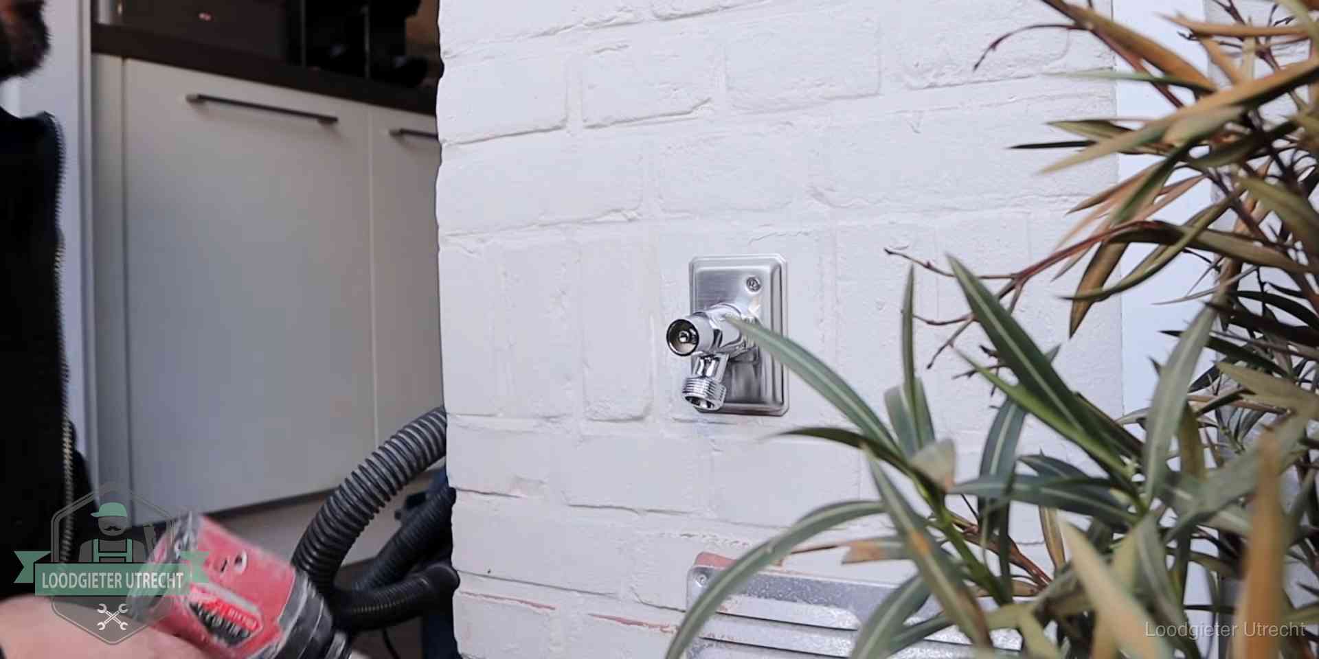 Chromen kraan op een muurplaat bij een woning in Utrecht, dichtdraaien is stap een van de lektest