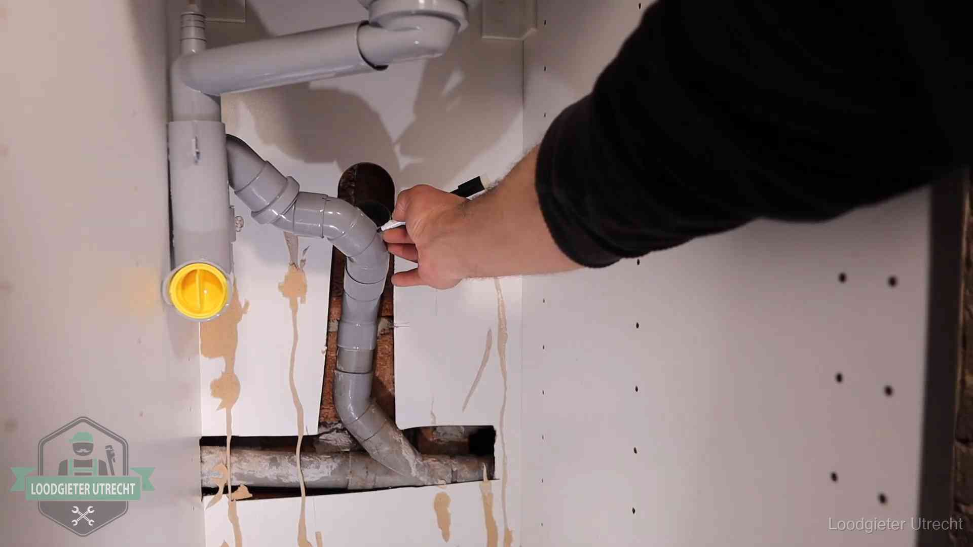 Loodgieter markeert een pvc-afvoerbuis onder een gootsteen in Utrecht