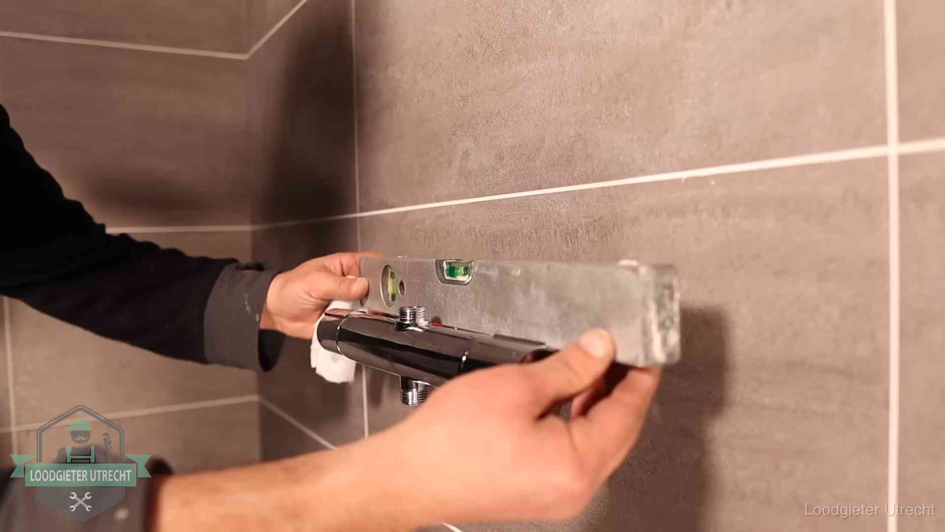 Loodgieter lijnt een douchekraan uit met een waterpas in een woning in Utrecht