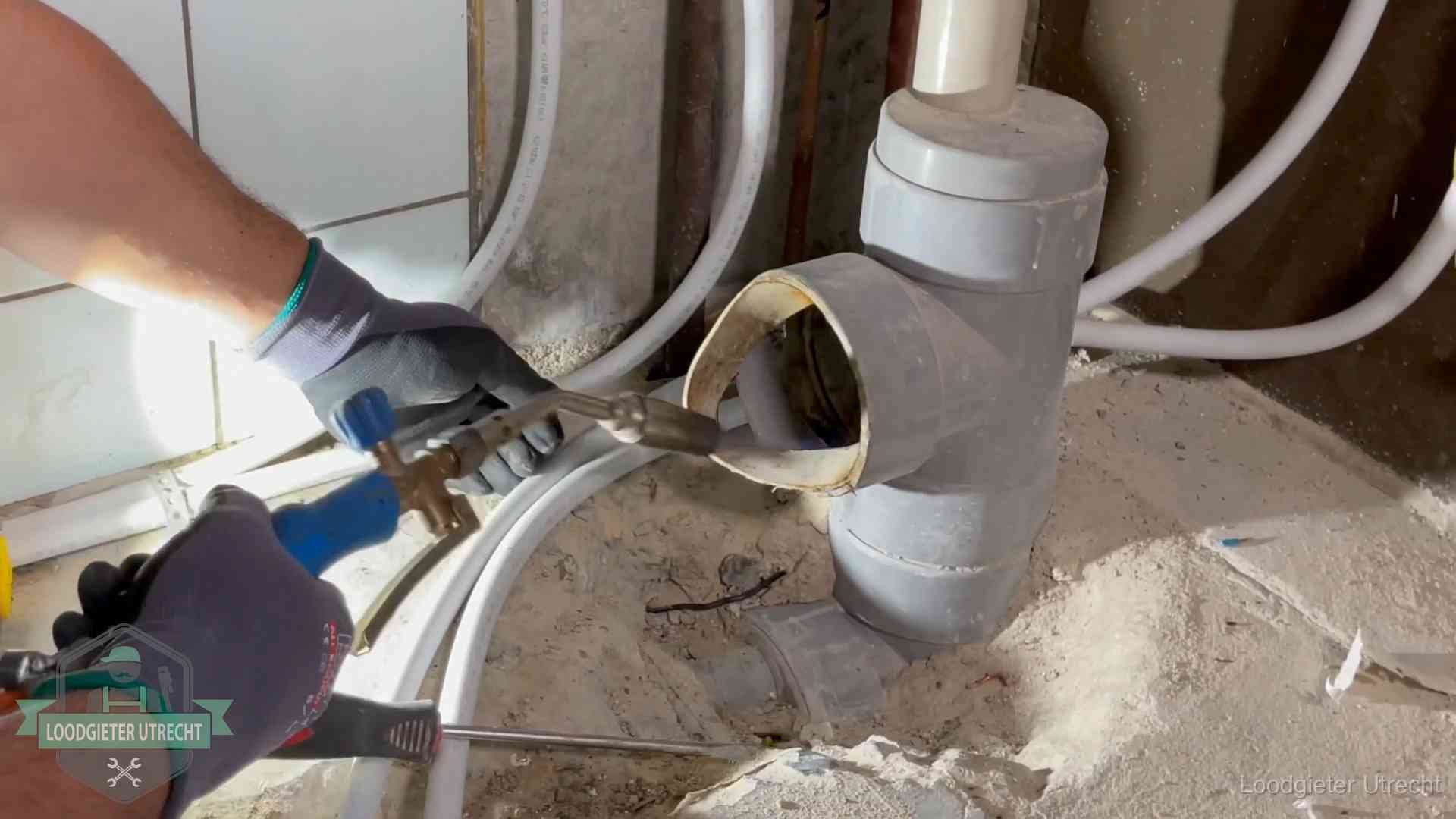 Loodgieter werkt met brander en messing kraanwerk aan leidingen in Utrecht