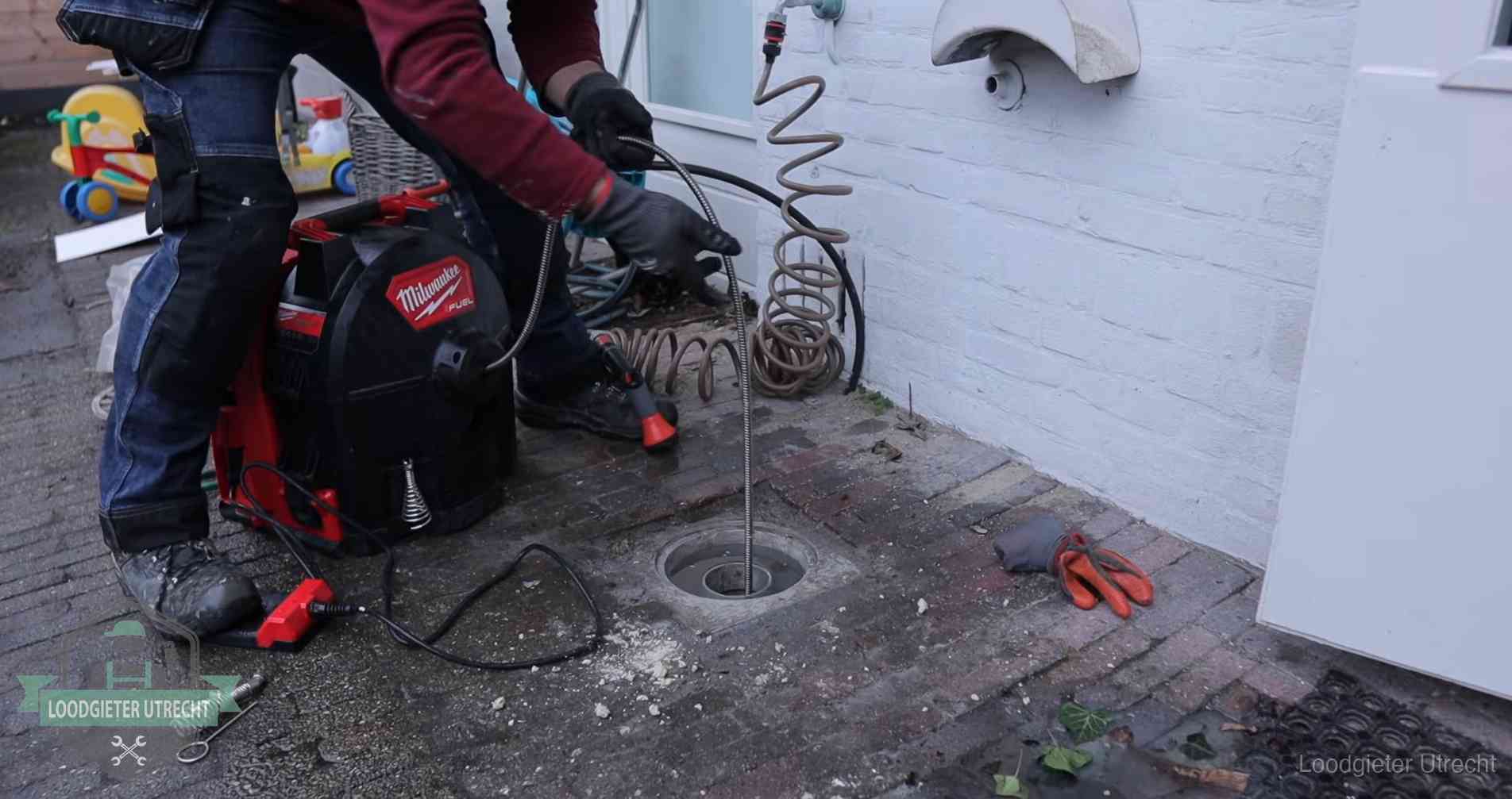 Ontstoppingsputje in de bestrating naast de gevel van een woning in Utrecht