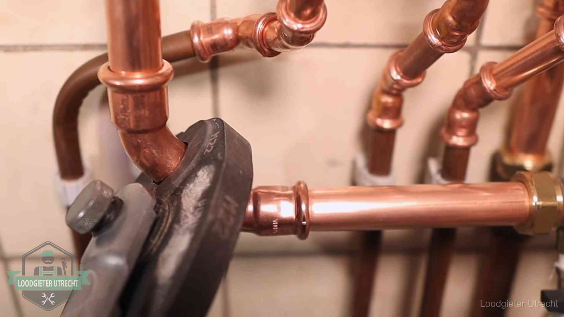Persmachine perst een koperen fitting op nieuw leidingwerk in Utrecht