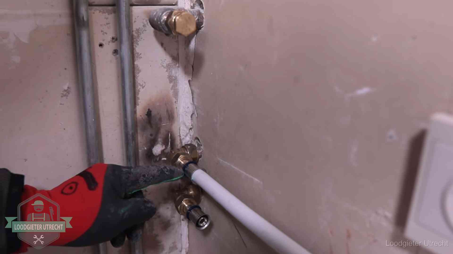 Loodgieter wijst de persfitting op nieuwe muuraansluitingen aan in een woning in Utrecht