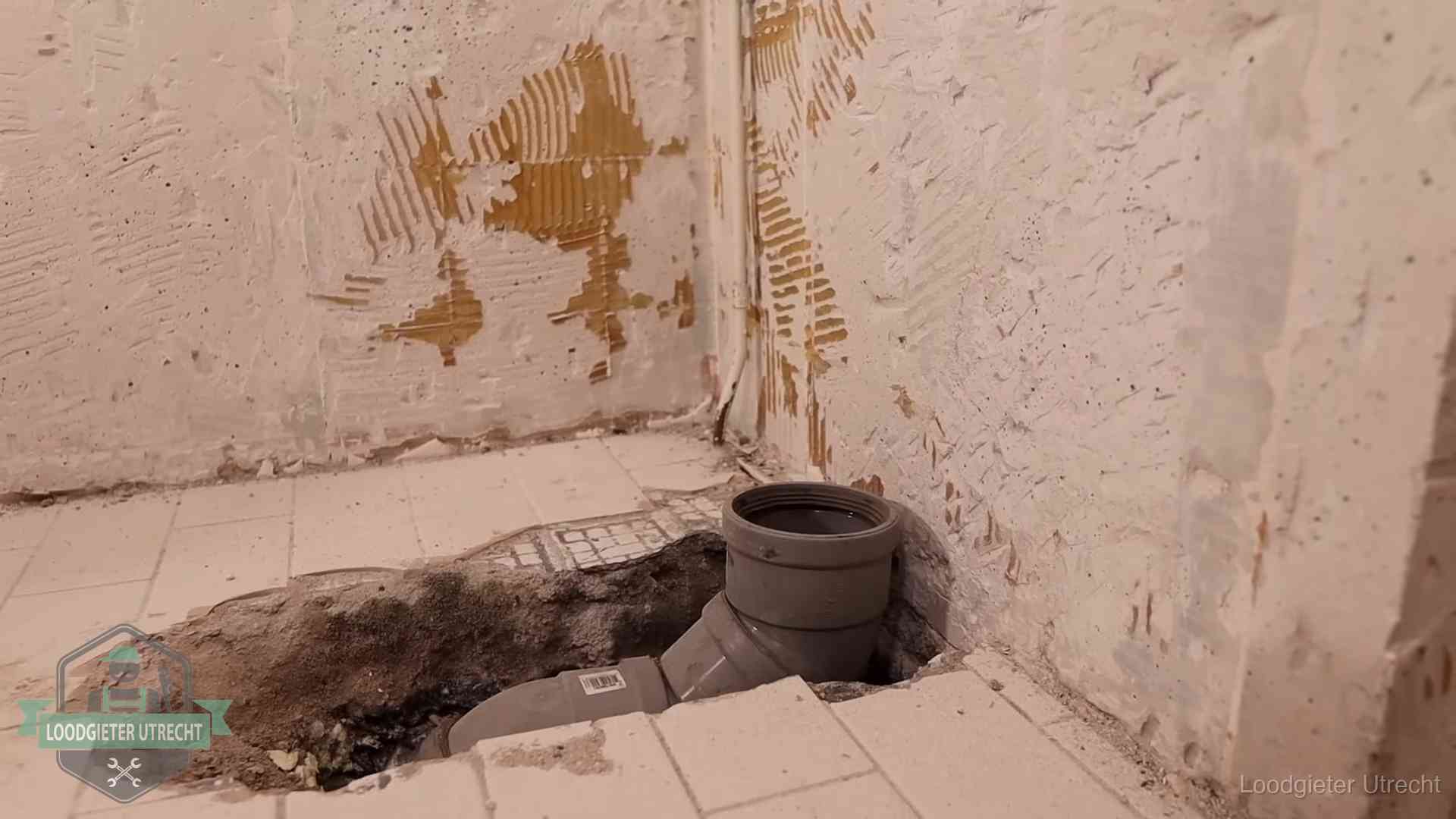 Opengebroken vloer met een nieuwe pvc-rioolbocht in een gegraven sleuf in Utrecht