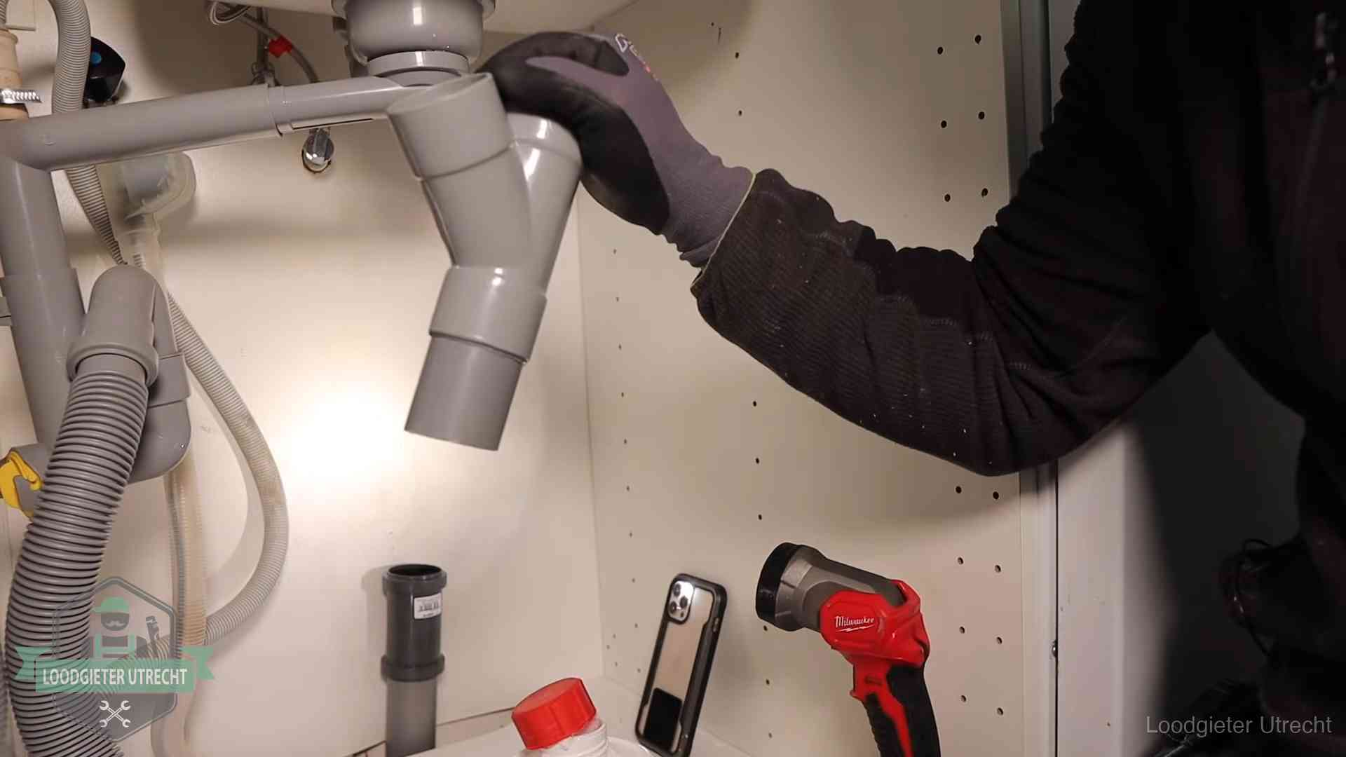 Loodgieter demonteert het sifon- en afvoerwerk onder een gootsteen in Utrecht bij stankklachten
