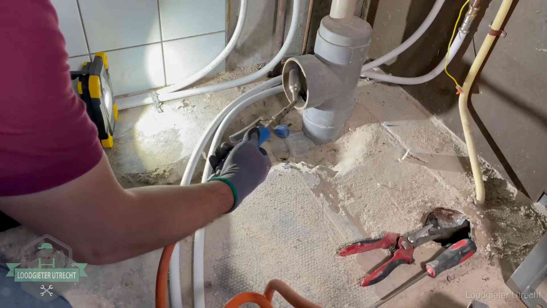 Loodgieter werkt aan leidingen bij een pvc-standleiding in een appartement in Utrecht