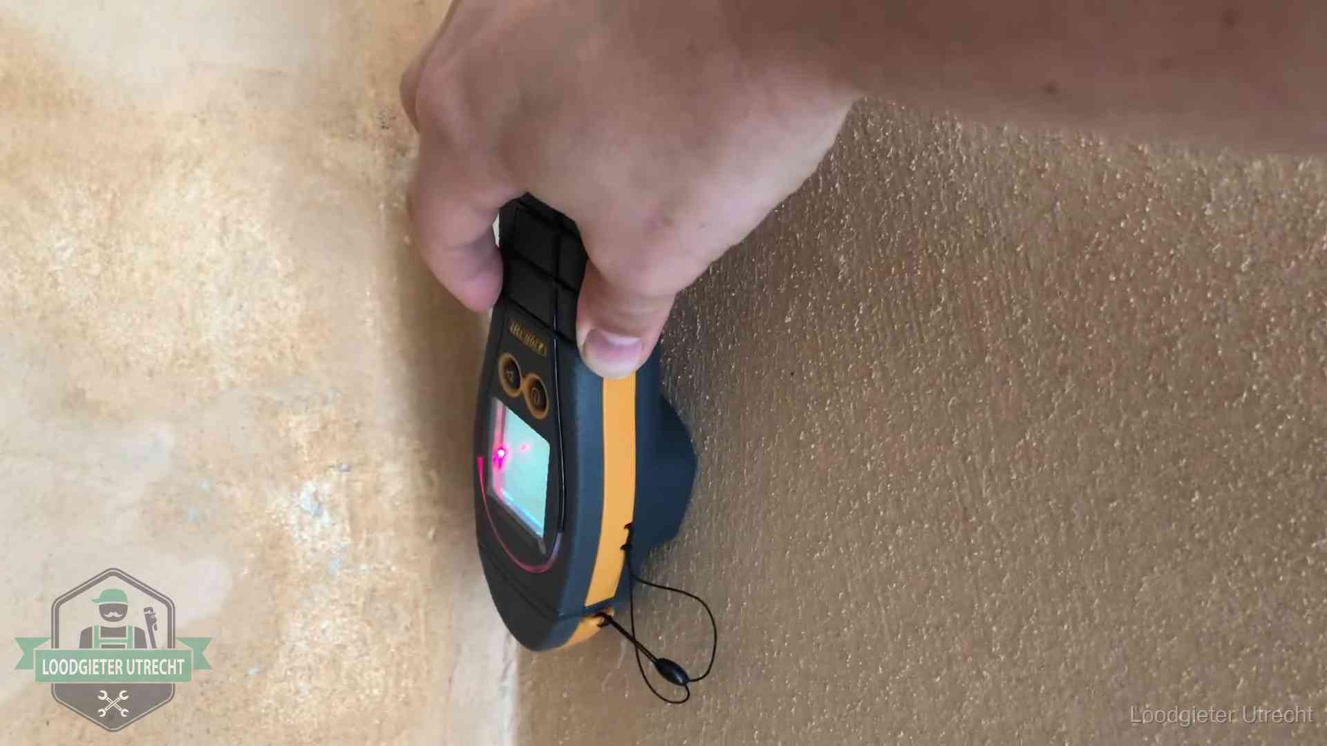Vochtmeter tegen een muur met vochtplekken tijdens het opsporen van een daklekkage in Utrecht